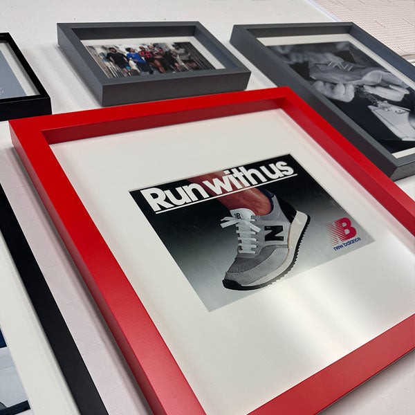 Brand-aligned custom framing featuring a red frame selected to reflect New Balance brand identity.