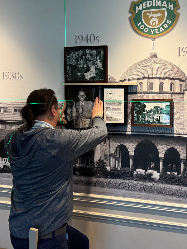 Professional installation of framed historic photographs in a corporate wall timeline display.