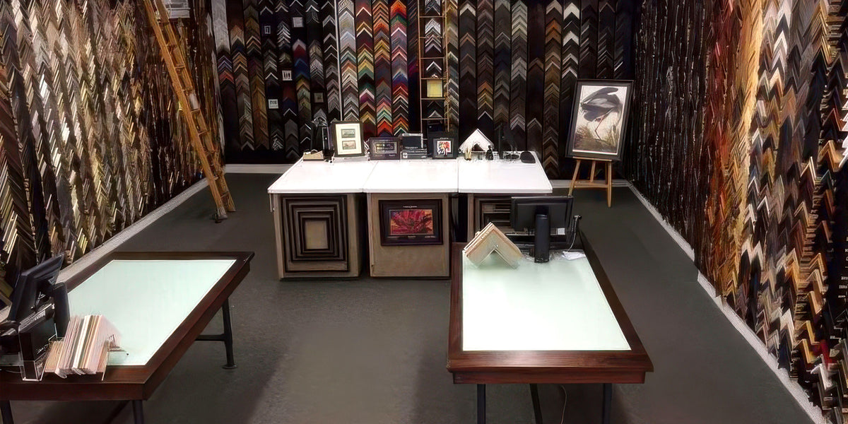 Interior of the original Goods of Evanston custom framing showroom, featuring walls of picture frame moulding samples, design counters and framed artwork.