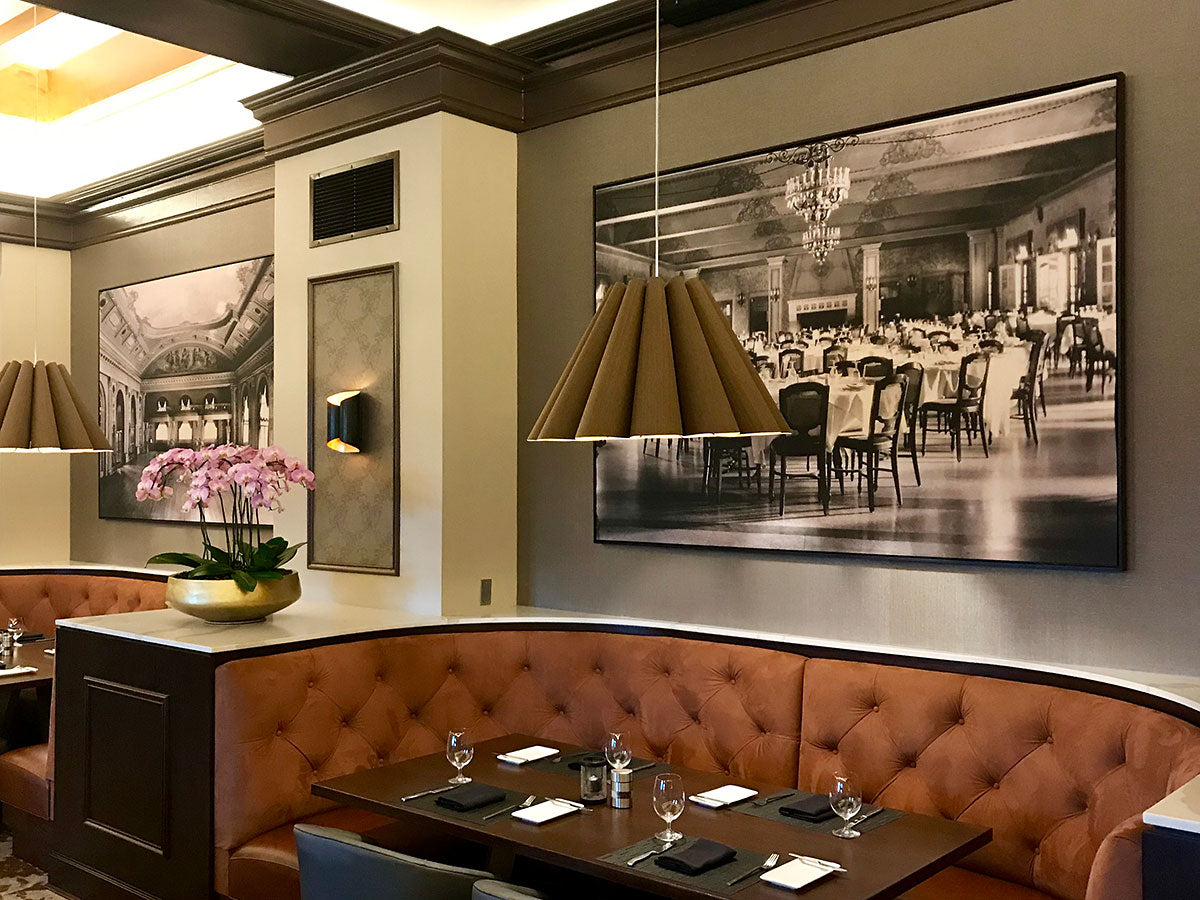 Large custom-framed black-and-white historical photographs installed above upholstered booths in an elegant restaurant dining room.