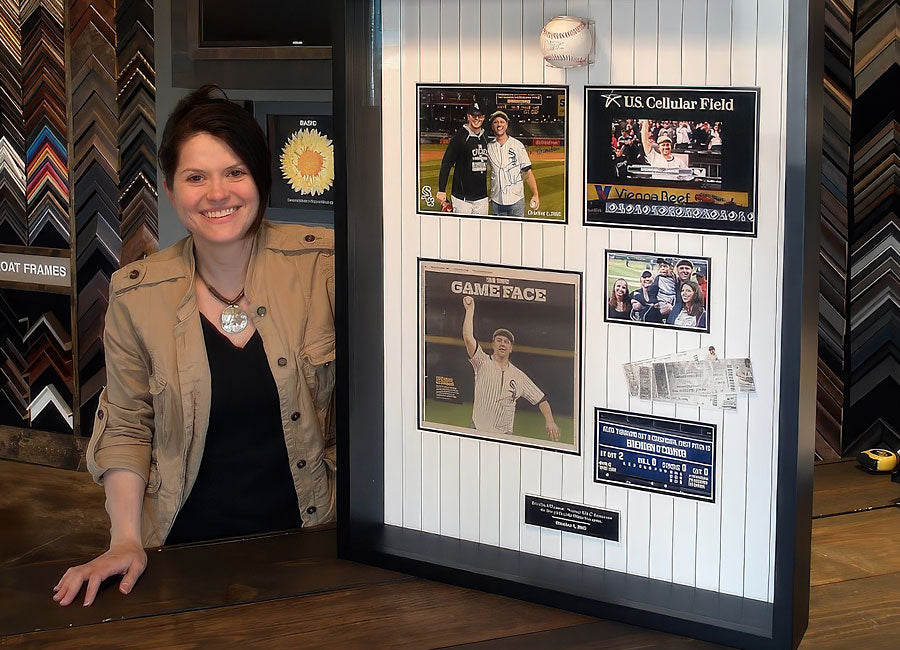 Customer poses beside a custom baseball memorabilia shadowbox featuring a signed baseball, photographs, ticket stubs and a scoreboard display.