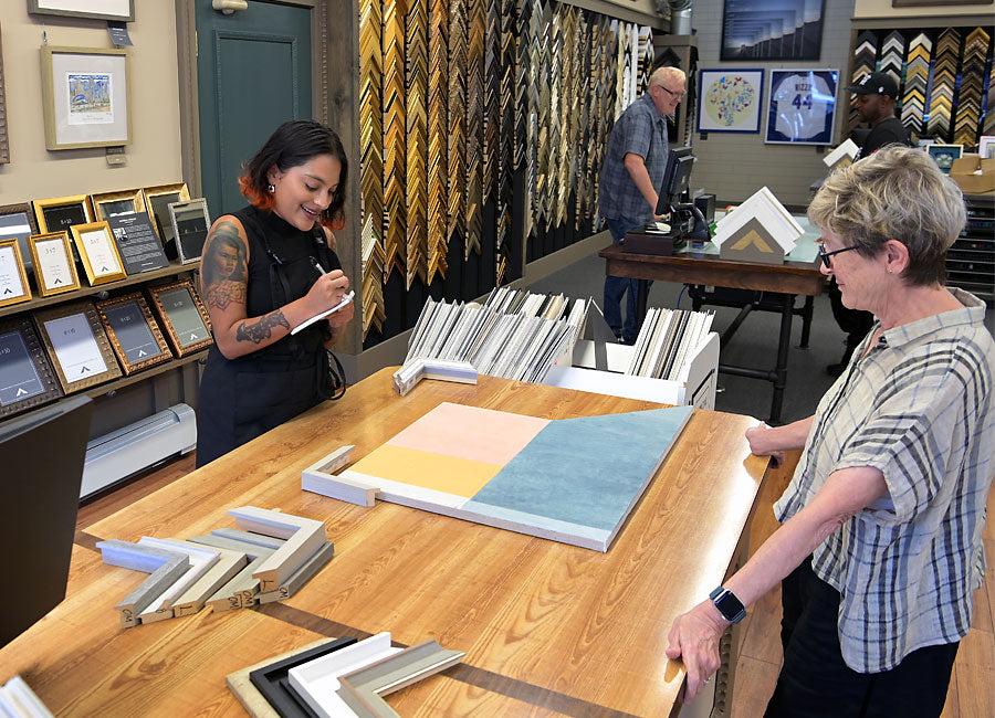 A framing designer reviews mat colors and frame samples with a customer at Masterpiece Framing & Imaging in Evanston.