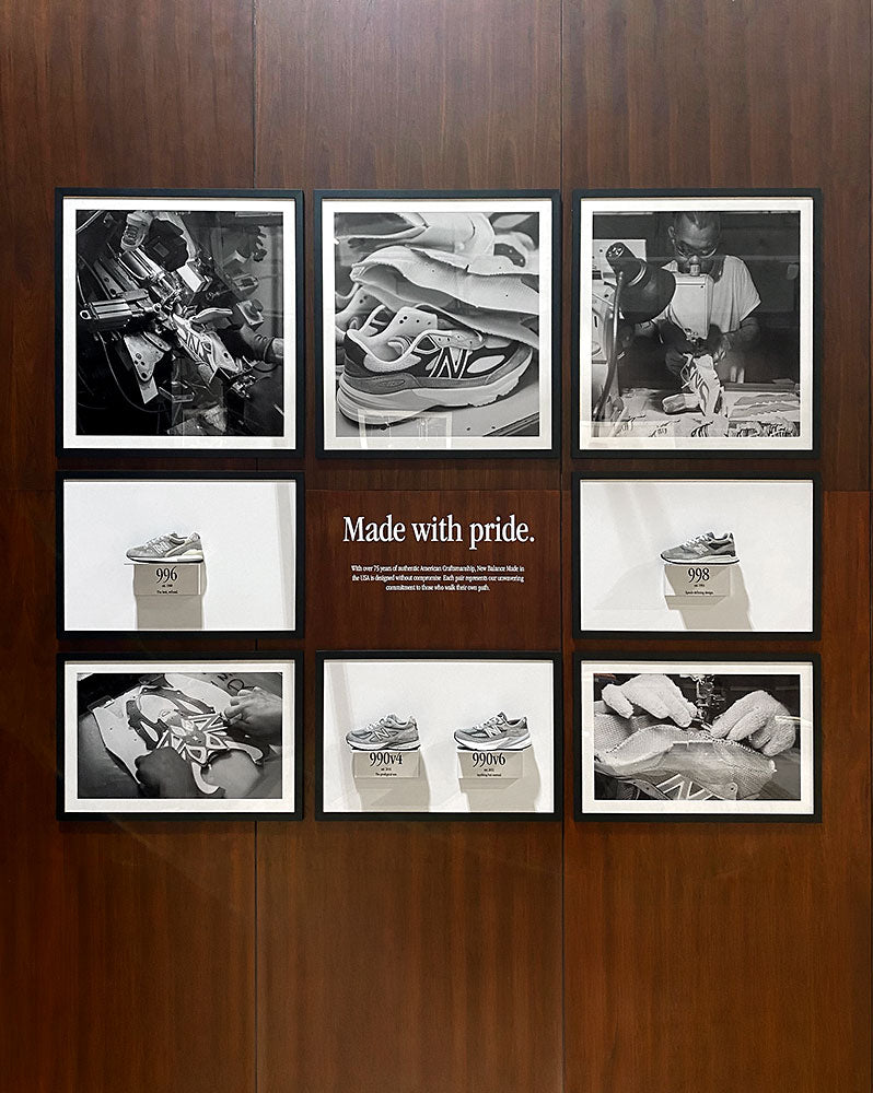 Custom corporate gallery wall for New Balance featuring eight black-framed photographs of sneaker manufacturing and footwear displays arranged around a Made with Pride message.