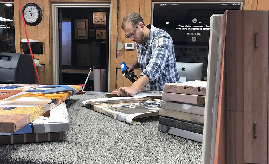A Masterpiece Framing & Imaging craftsman stretches printed canvas over wooden stretcher bars using a pneumatic staple gun in our workshop.