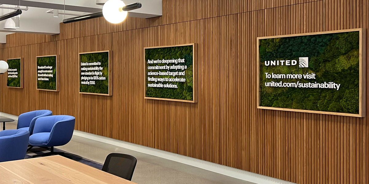 Custom-framed sustainability messaging displays for United Airlines, featuring natural wood frames and green textured backgrounds installed on a wood-paneled wall in a Chicago corporate space.